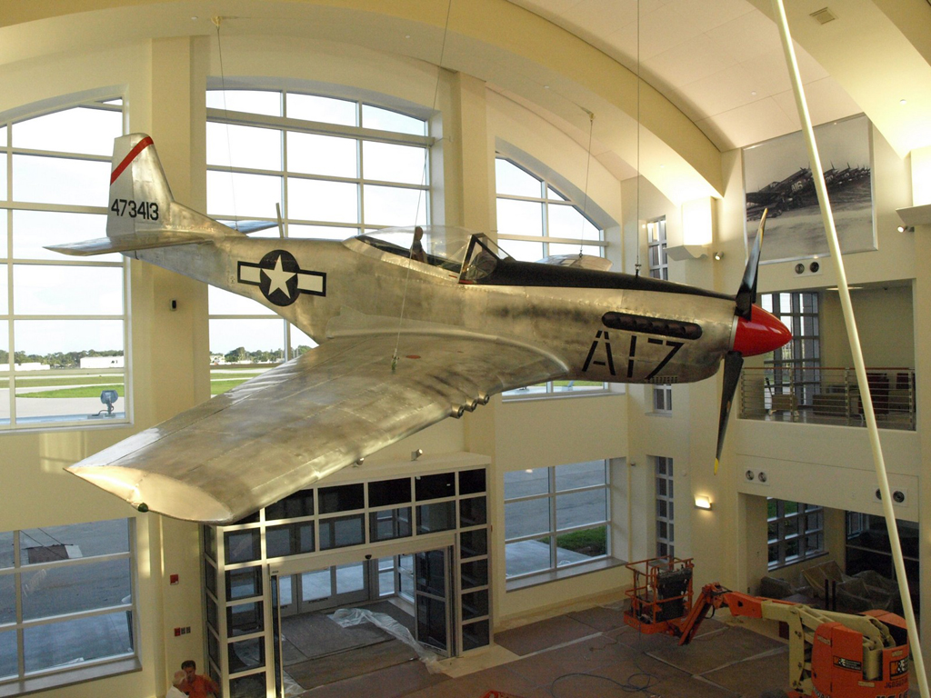 A P51 Mustang fighter plane on display hanging from the ceiling of